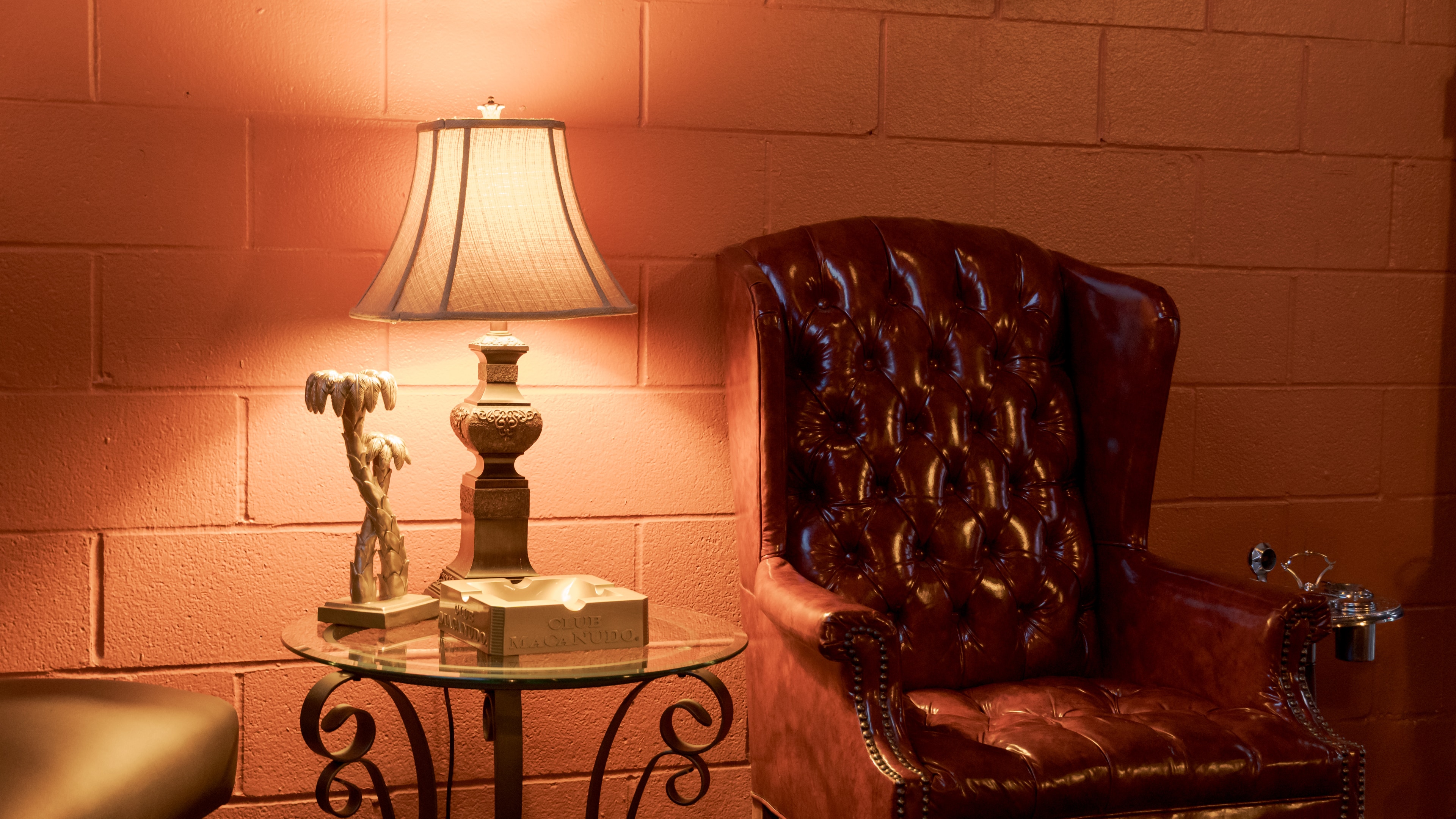 A tufted leather chair beside a lit table lamp at The Bay