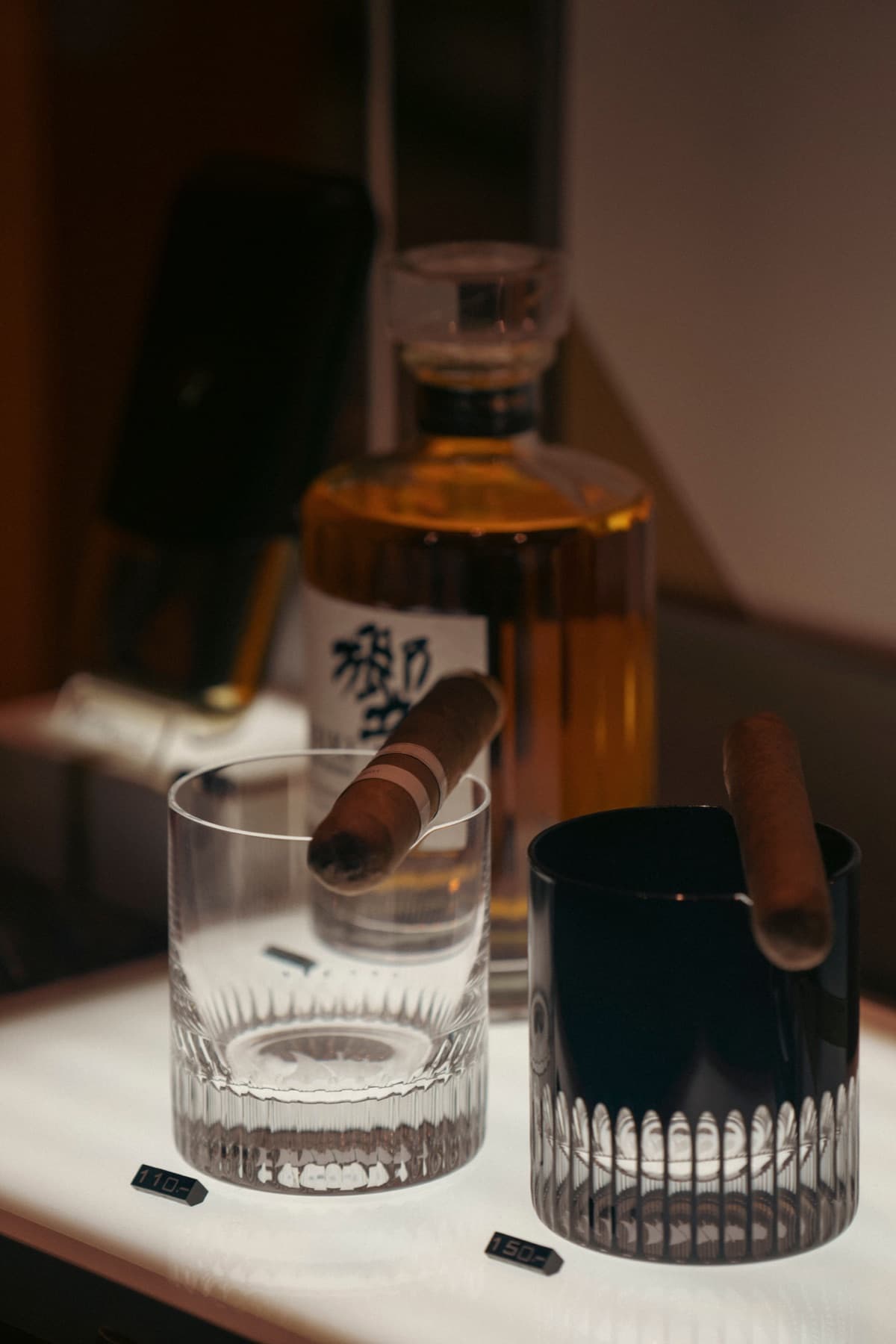 A cigar, glassware, and whiskey arranged for an evening